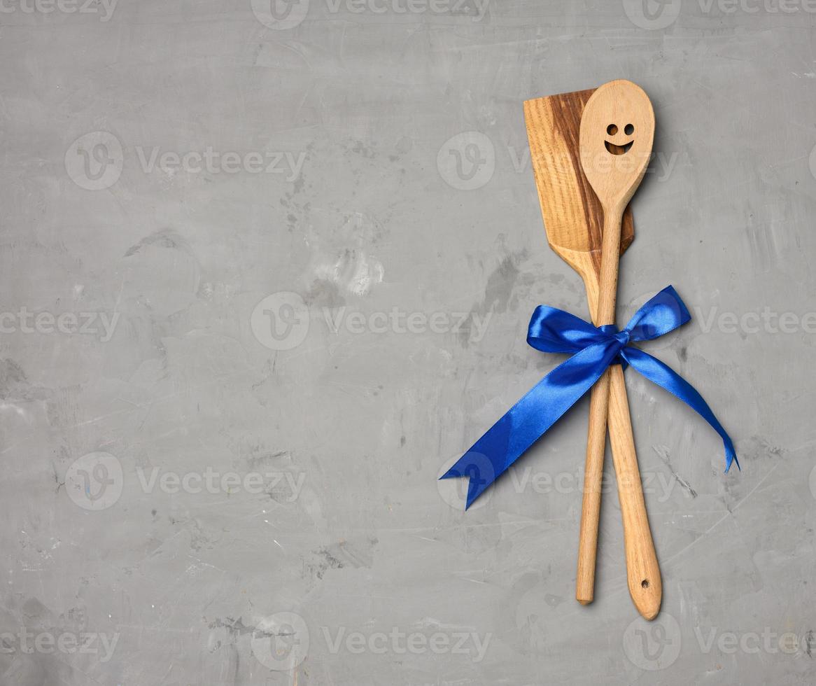 spoon and spatula tied with blue ribbon on gray background photo