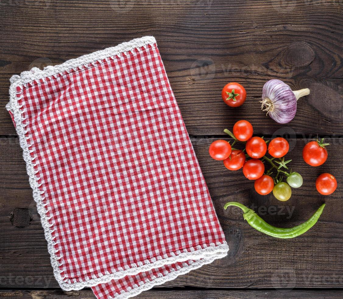toalla de cocina textil roja en una jaula y tomates cherry frescos foto