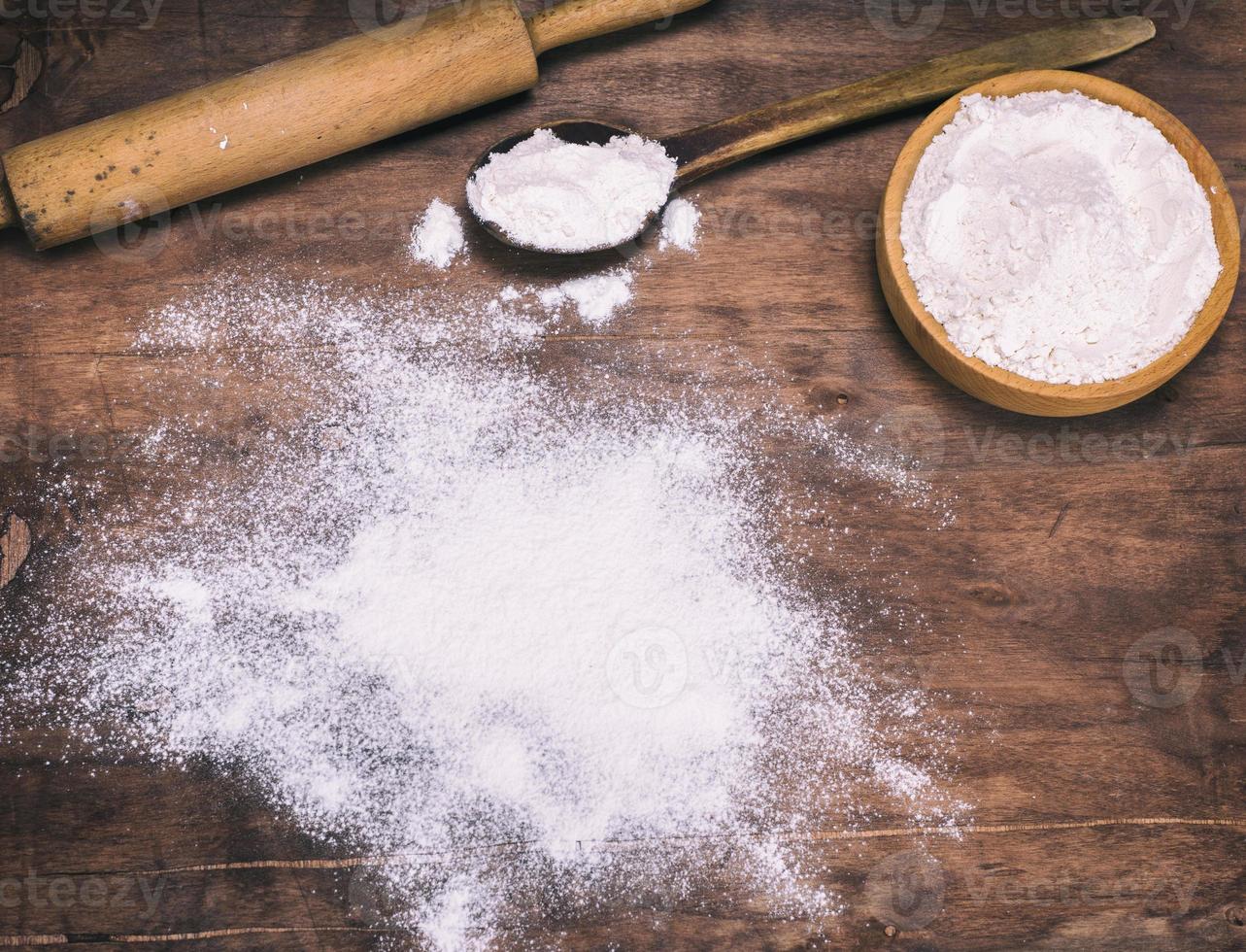 scattered white wheat flour on a brown wooden background photo