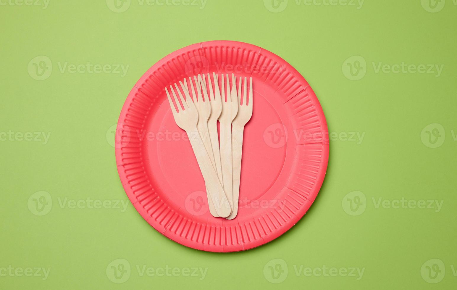 Wooden fork and empty round red disposable plate photo