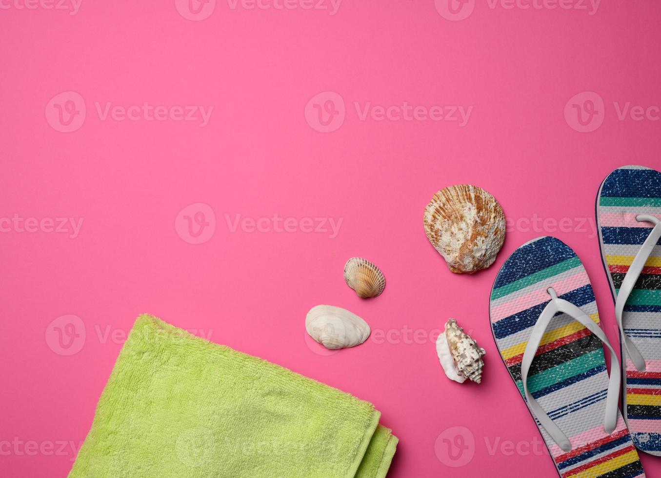 women's multicolored slippers and seashell on pink background photo