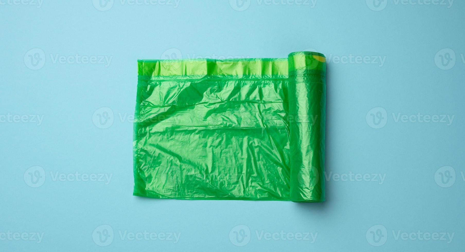 roll of green transparent plastic bags for trash can on blue background photo