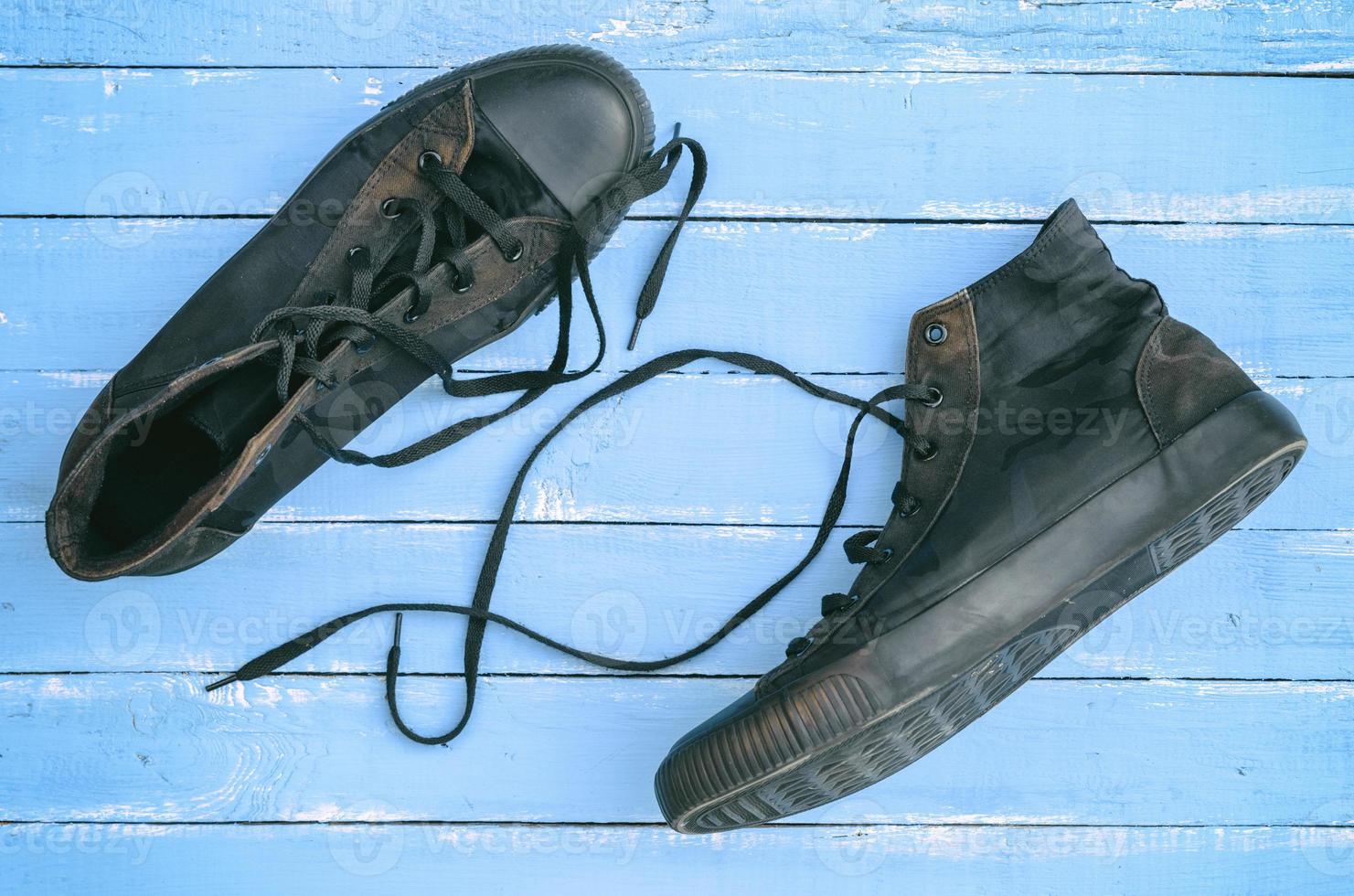un par de viejas zapatillas negras en mal estado con cordones sueltos foto