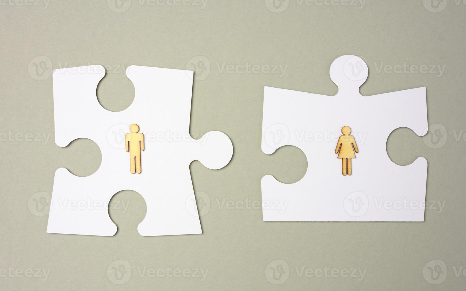 white puzzles and wooden men on a gray background. Recruitment concept, team compatibility, individuality. photo