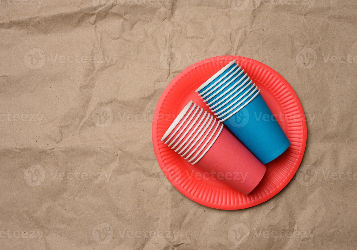 stack of paper cups and round plates on a brown paper background photo