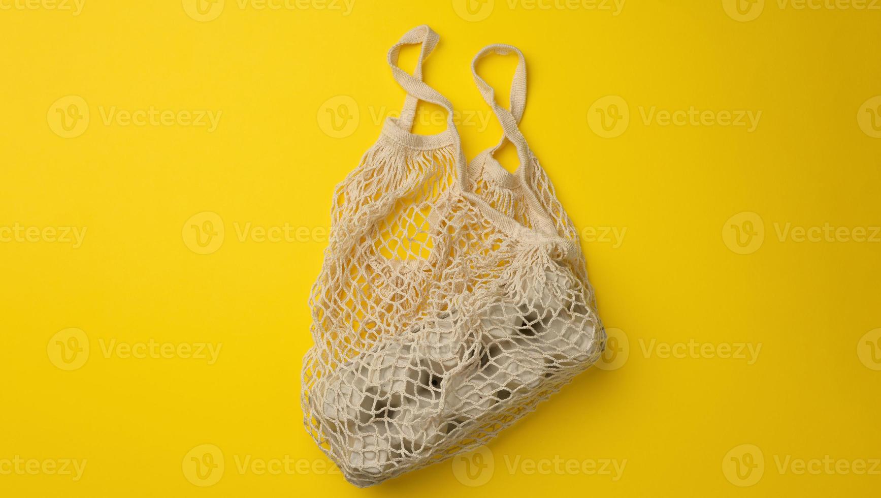 reusable white textile shopping bag with egg cartons on a yellow background, zero waste, photo