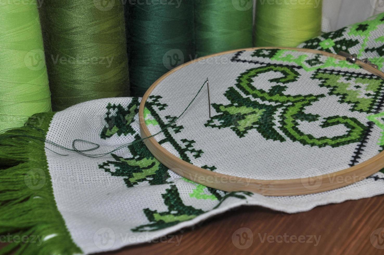 el aro de bordado con lienzo e hilos de coser brillantes para bordar en la mesa foto