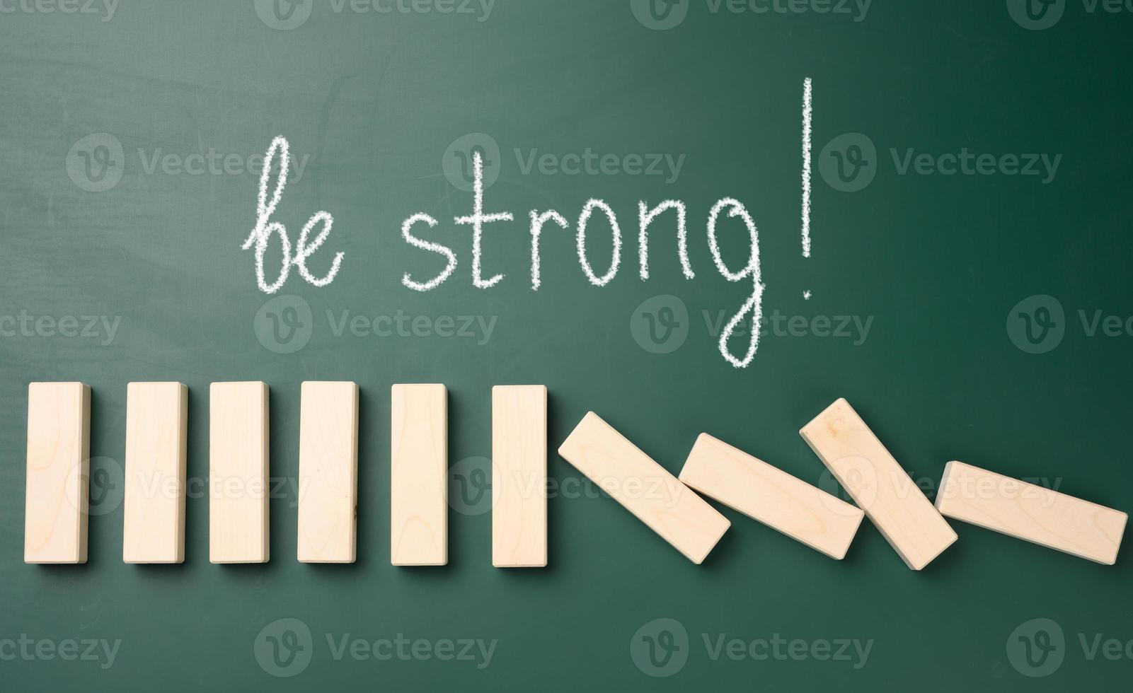 falling wooden blocks on a green background and the inscription be strong. Strong personality concept photo