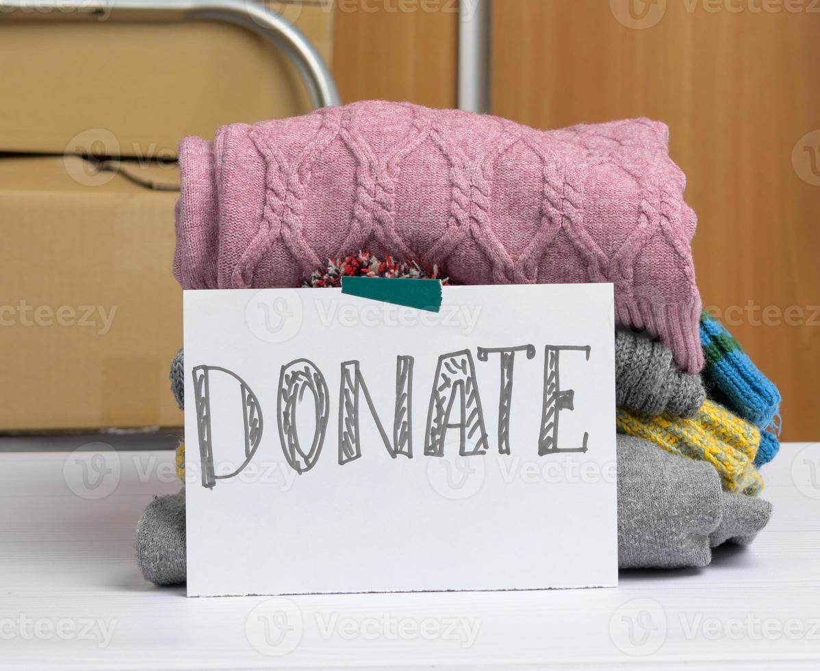 sheet of paper with an inscription donate and a stack of clothes photo