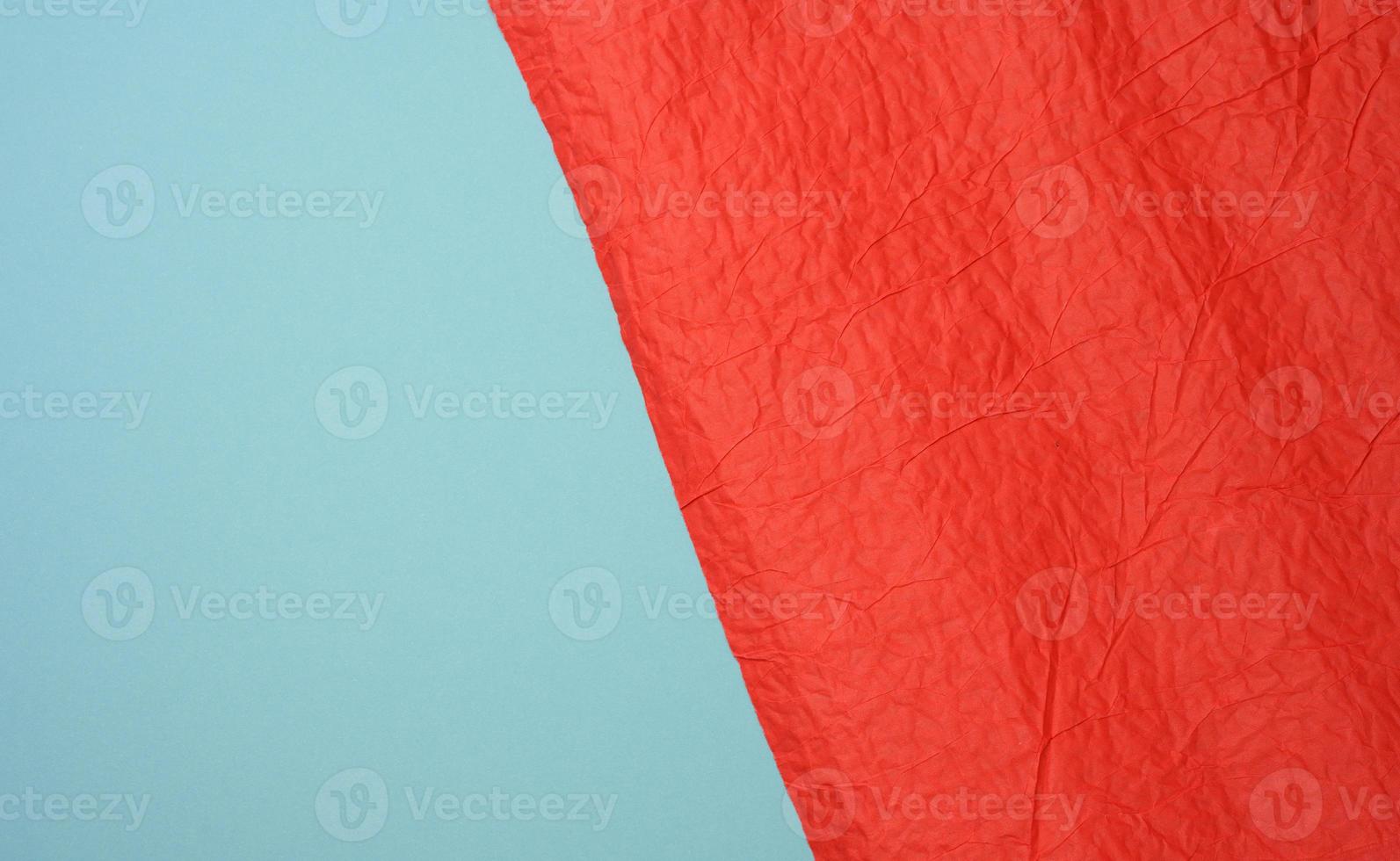 crumpled sheet of red paper on a blue background photo