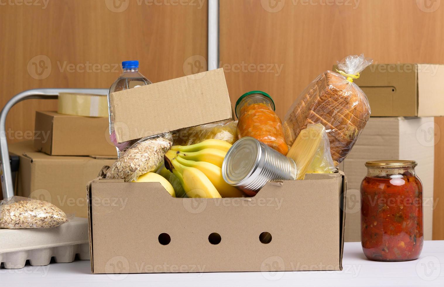 cardboard box with various products, fruits, pasta, sunflower oil in a plastic bottle and preservation photo