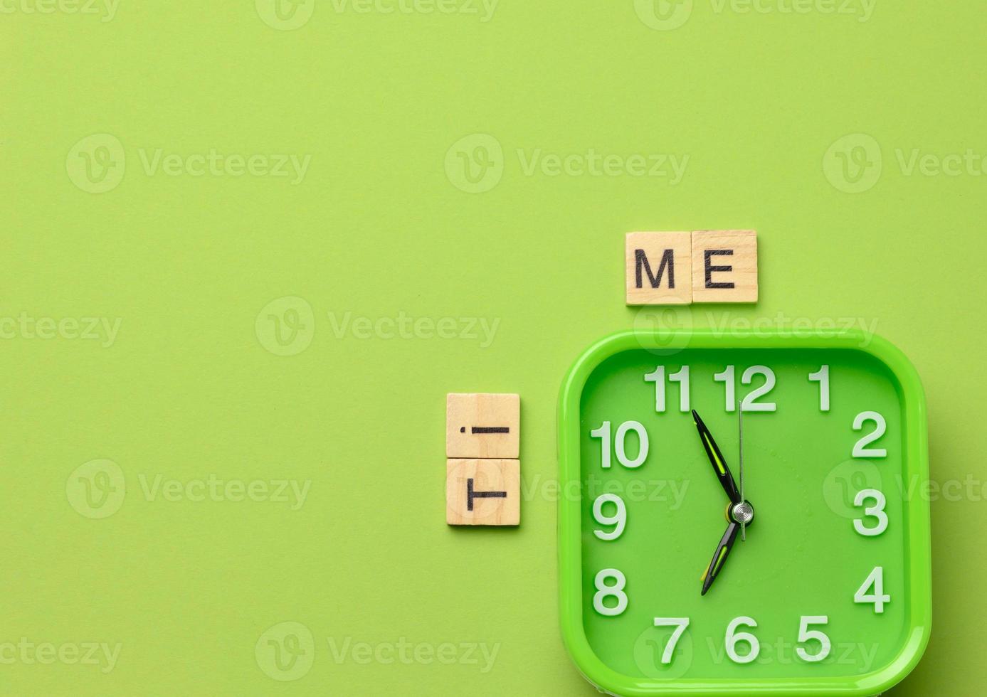 square green alarm clock on a green background and the inscription time photo