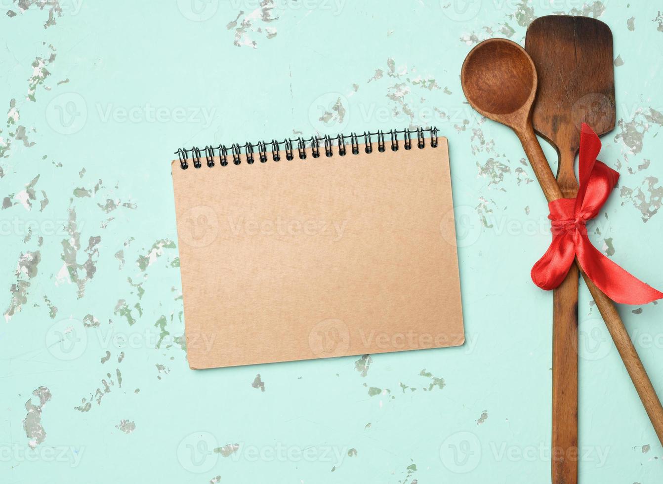 spoon and spatula tied with blue ribbon on green background photo