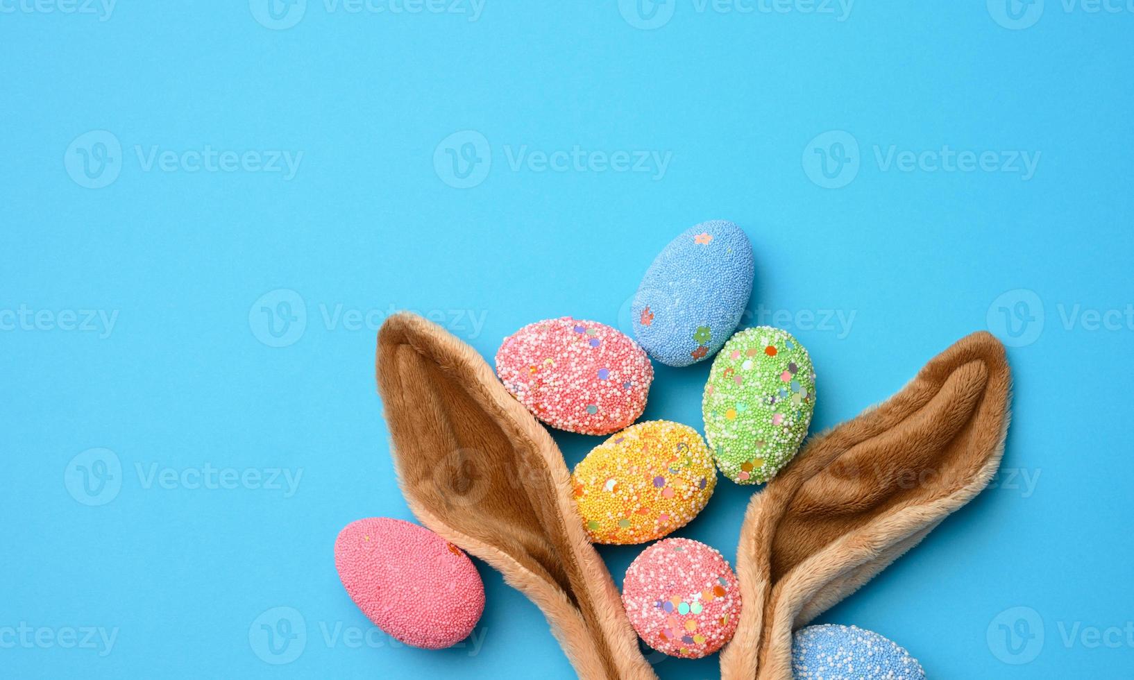 decorative easter eggs and long ears plush bunny toy on a blue background photo