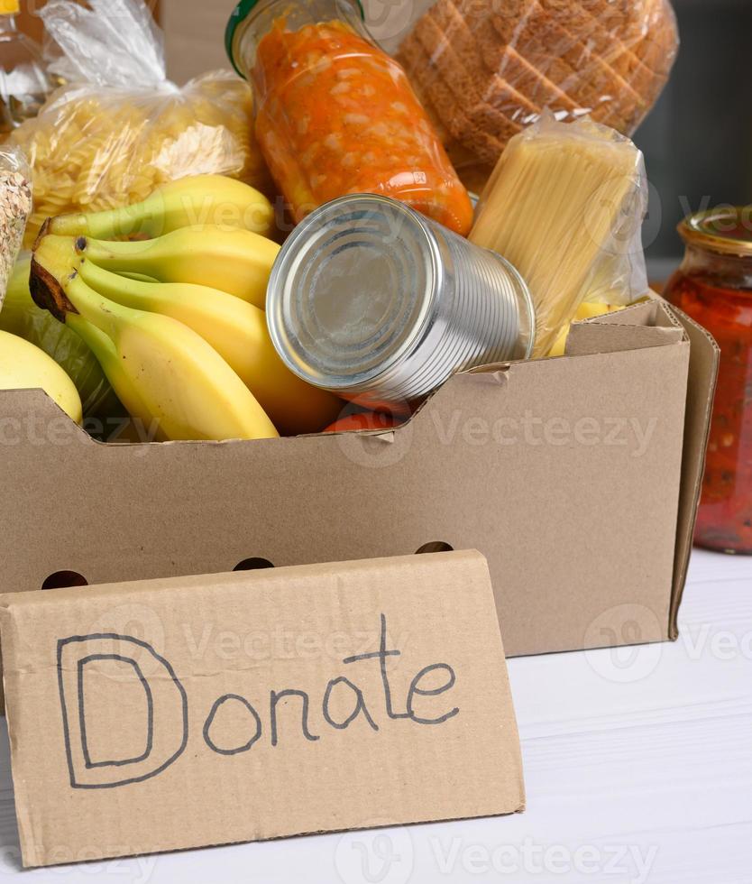 caja de cartón con varios productos, frutas, pasta en botella de plástico y conservación foto