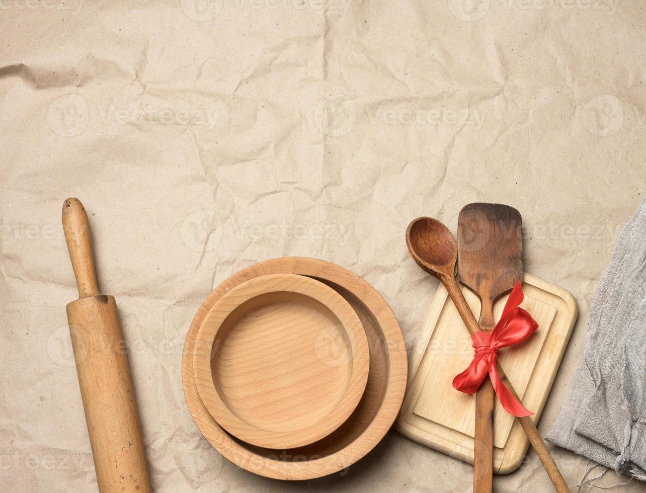 spoon and spatula tied with red ribbon on a brown paper background and wooden rolling pin photo