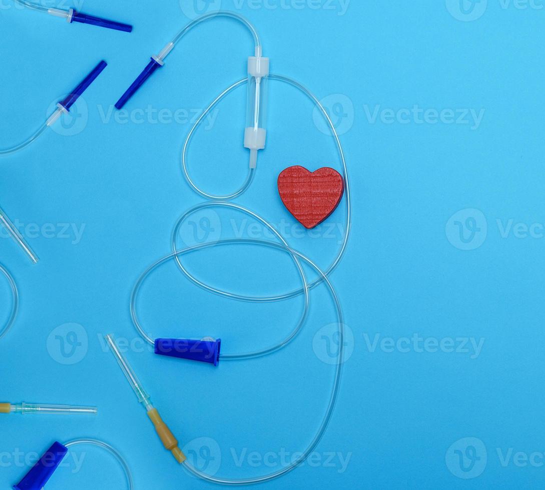 empty plastic dropper with needles and red heart on blue background, medical device photo