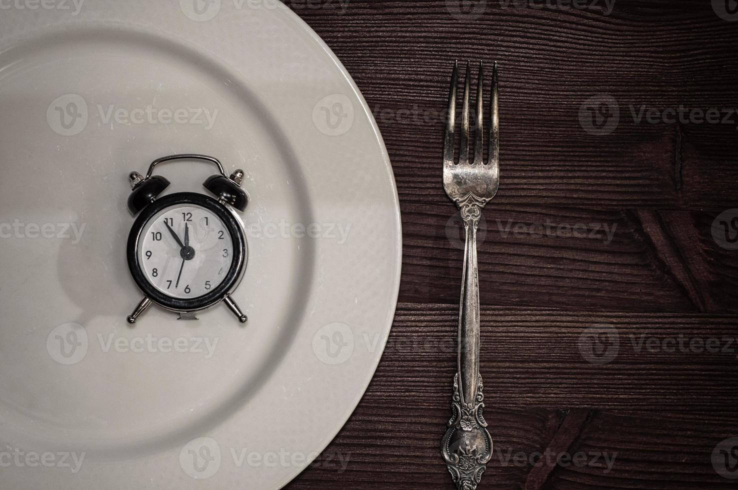 Vintage clocks lie in a white plate, next is fork photo