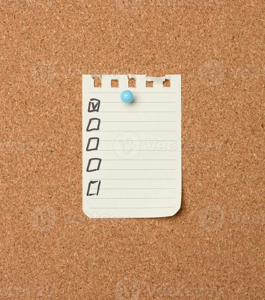 blank sheet of paper in a line attached with a plastic button on a brown cork board photo