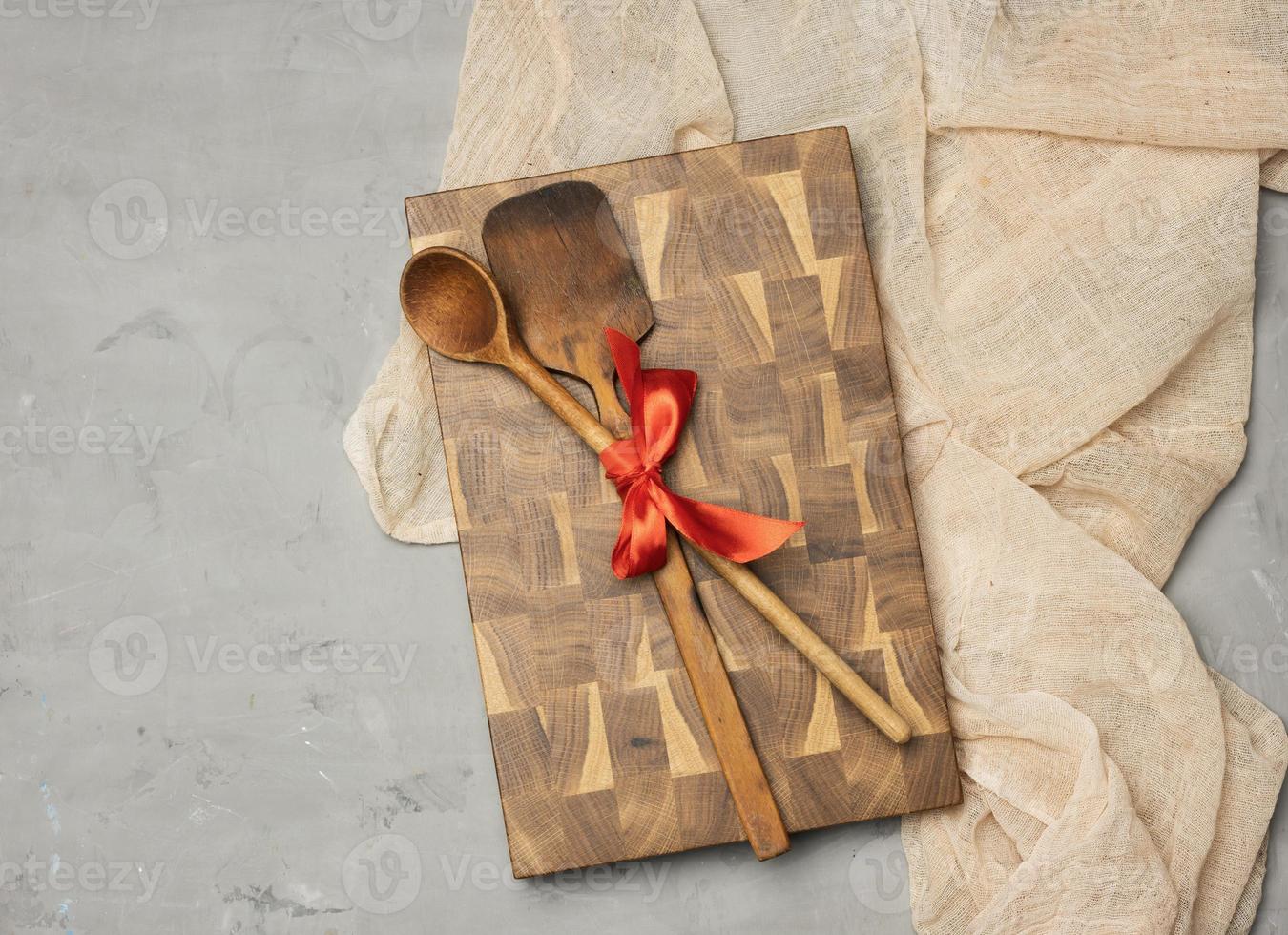 old spoon and spatula tied with red ribbon on a gray background photo