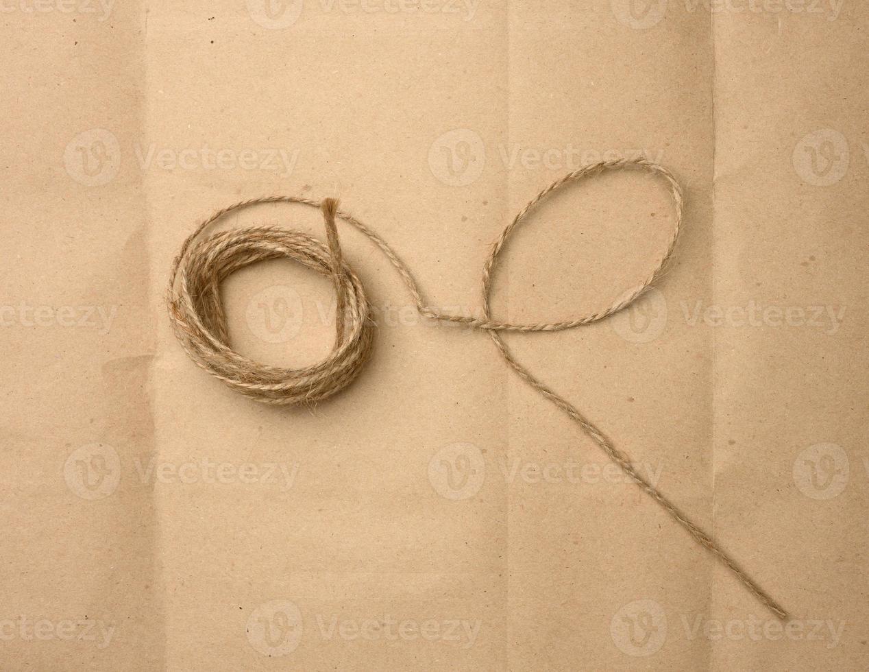 brown folded twine on a brown paper background, rope for household needs photo