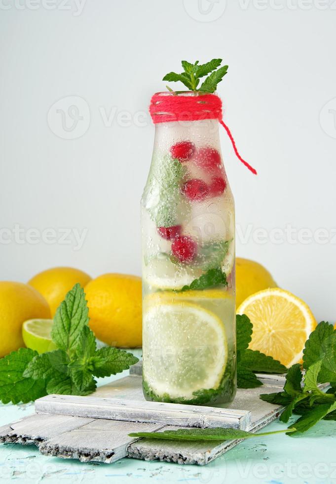summer refreshing drink lemonade with lemons, mint leaves, lime in a glass bottle photo