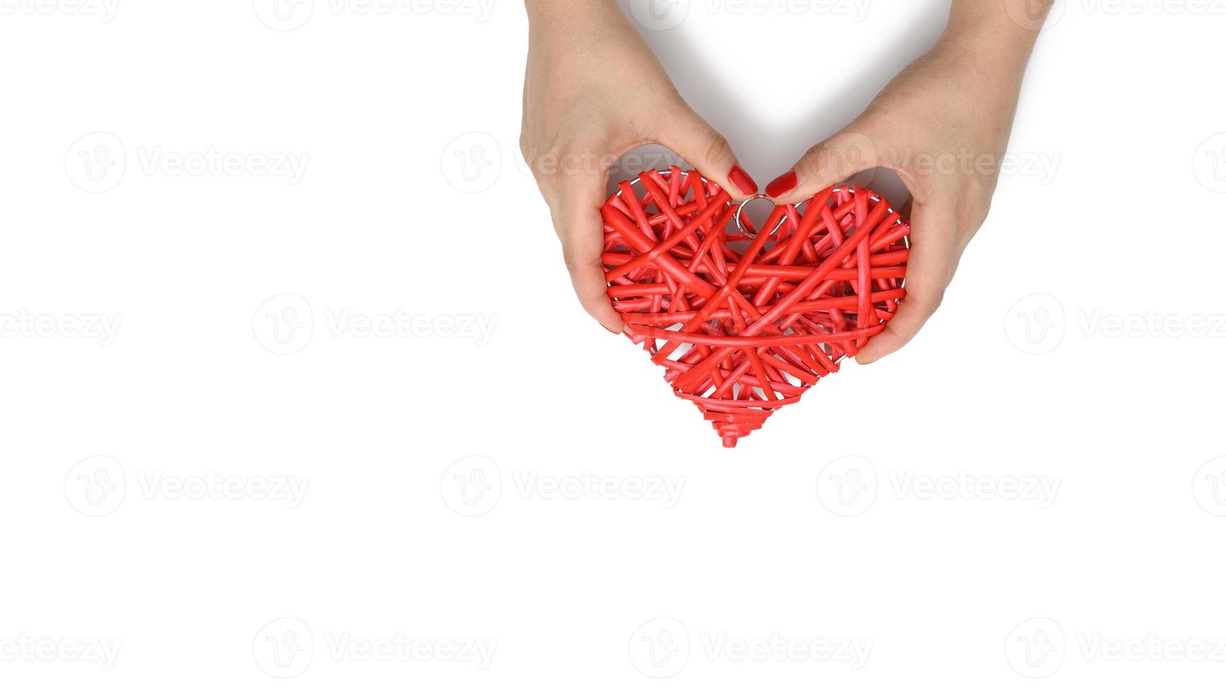 two female hands hold a red wicker heart on a white background, the concept of gratitude, kindness photo