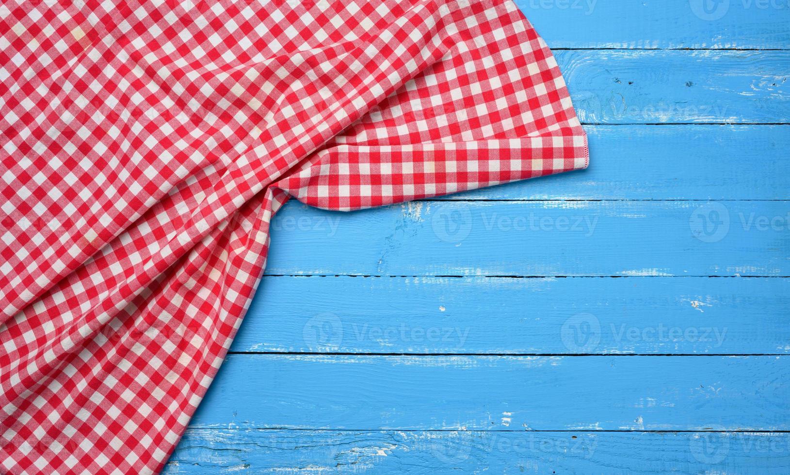 servilleta de cocina de algodón rojo y blanco doblada sobre un fondo azul de madera foto