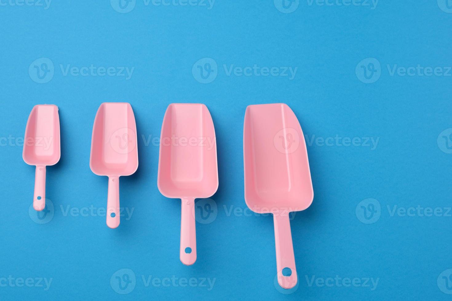 set of pink plastic kitchen scoops for bulk products on a blue background photo