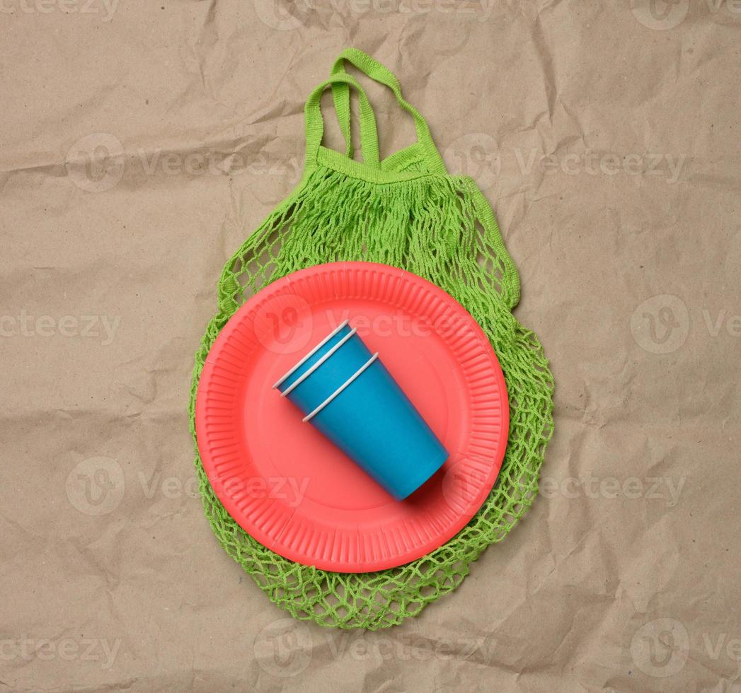 stack of blue paper cups and red round plates on a brown paper background photo