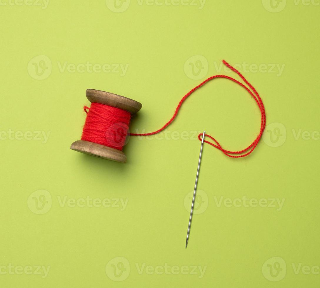 wooden spool with red wool thread on a green background photo