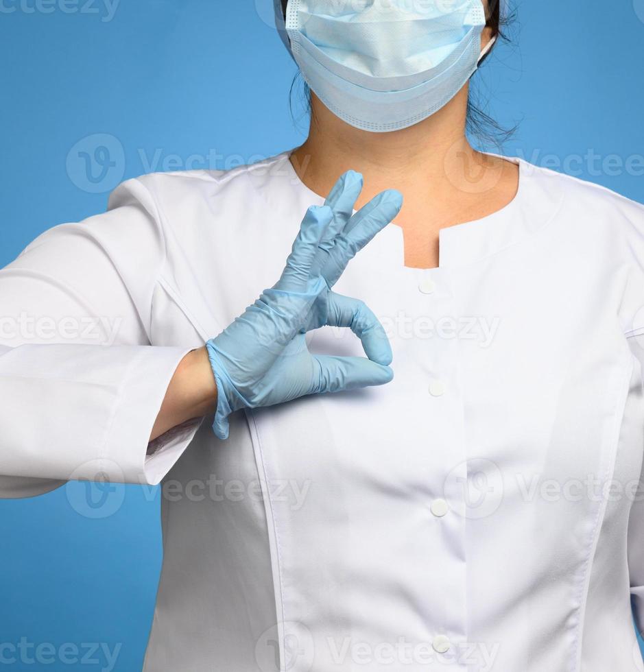 woman in white coat, wearing blue medical latex gloves on her hands photo