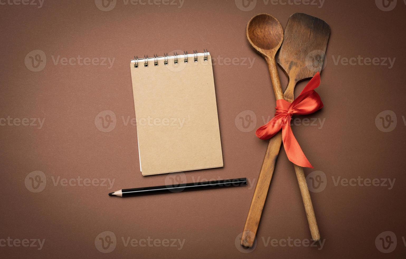 old spoon and spatula tied with red ribbon on a brown background, top view, copy space photo