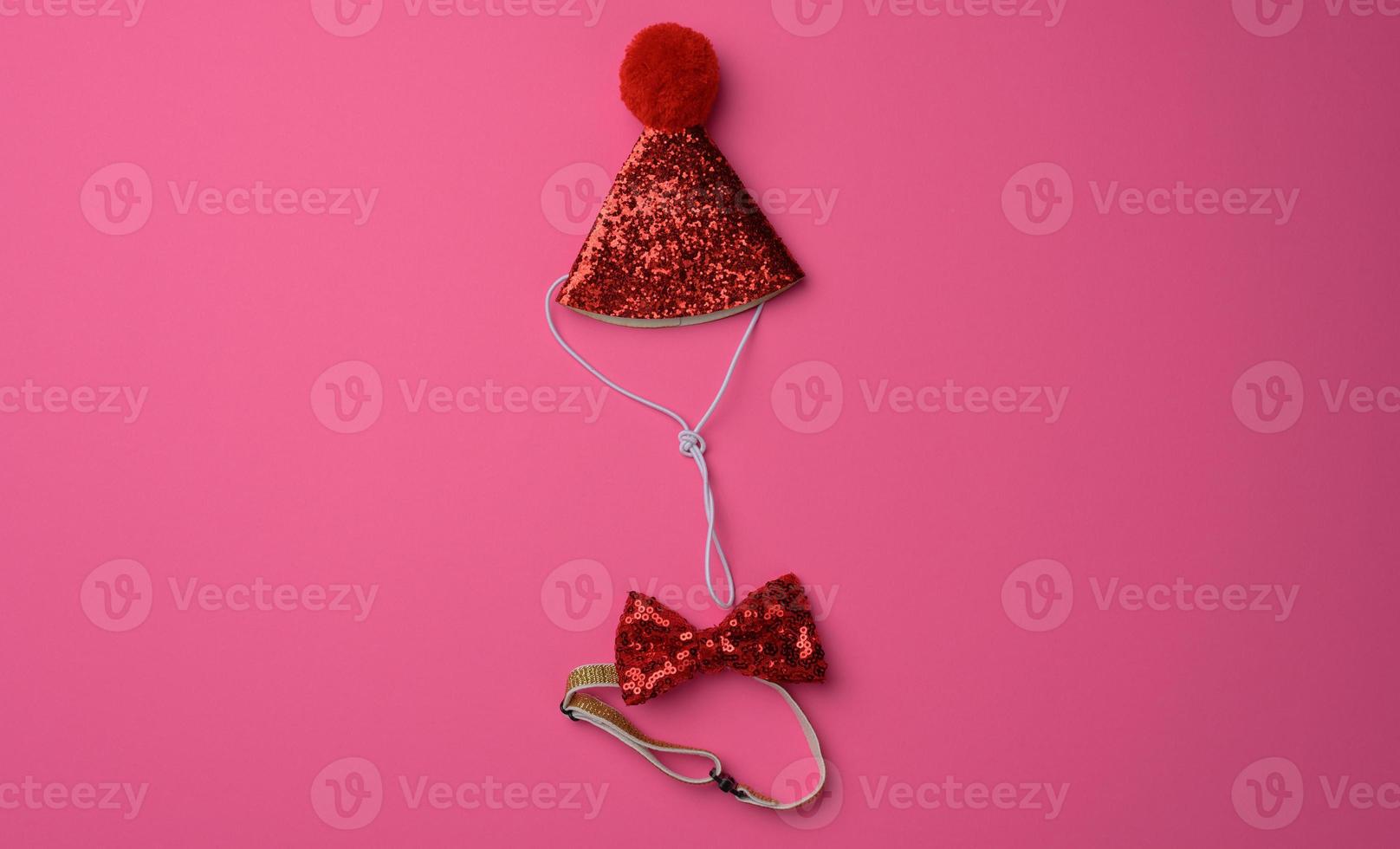red cap and a butterfly on the neck with sequins on a pink background. Festive costume photo