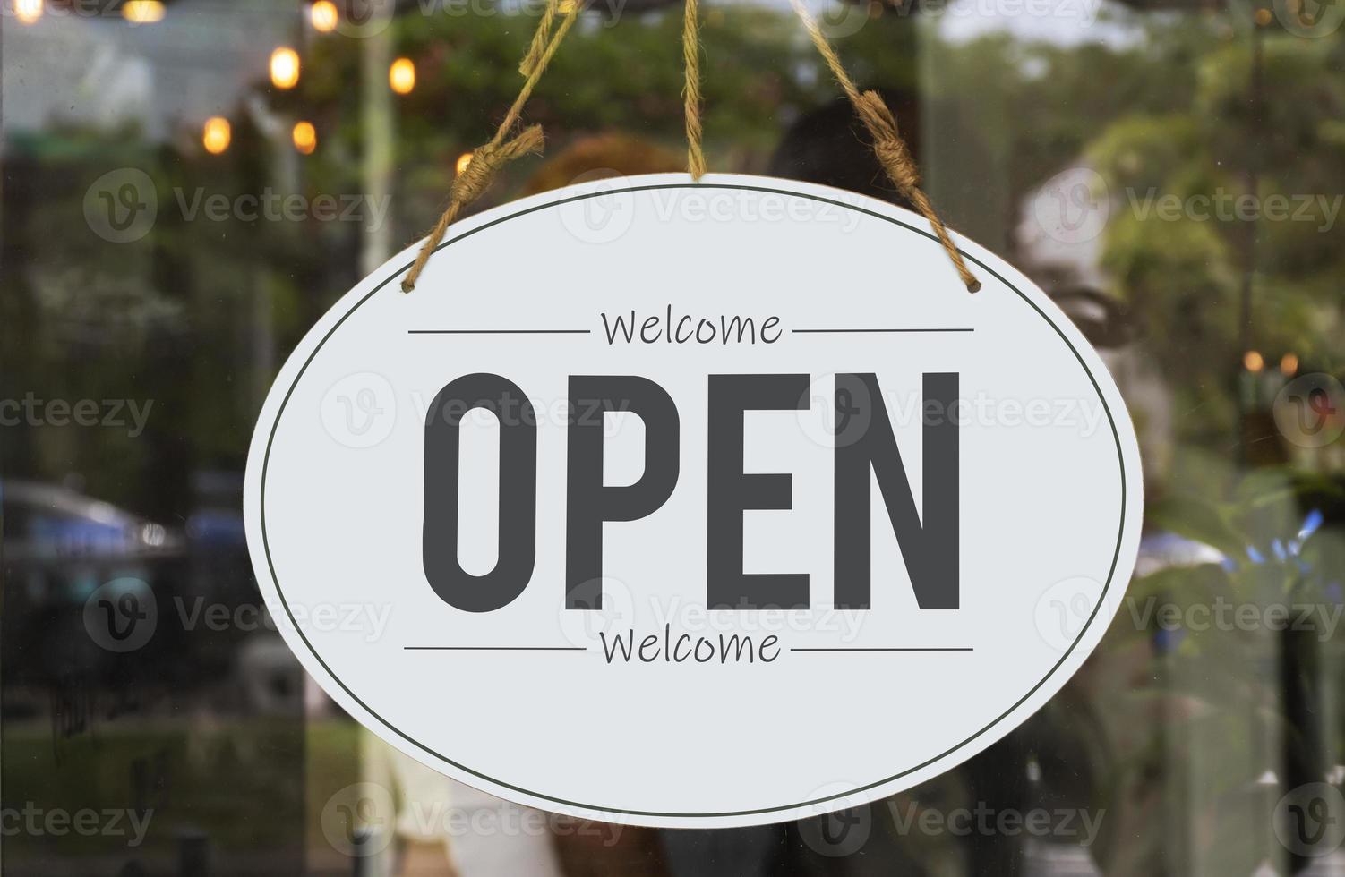 Hanging sign with message Welcome OPEN on glass door at coffee shop photo