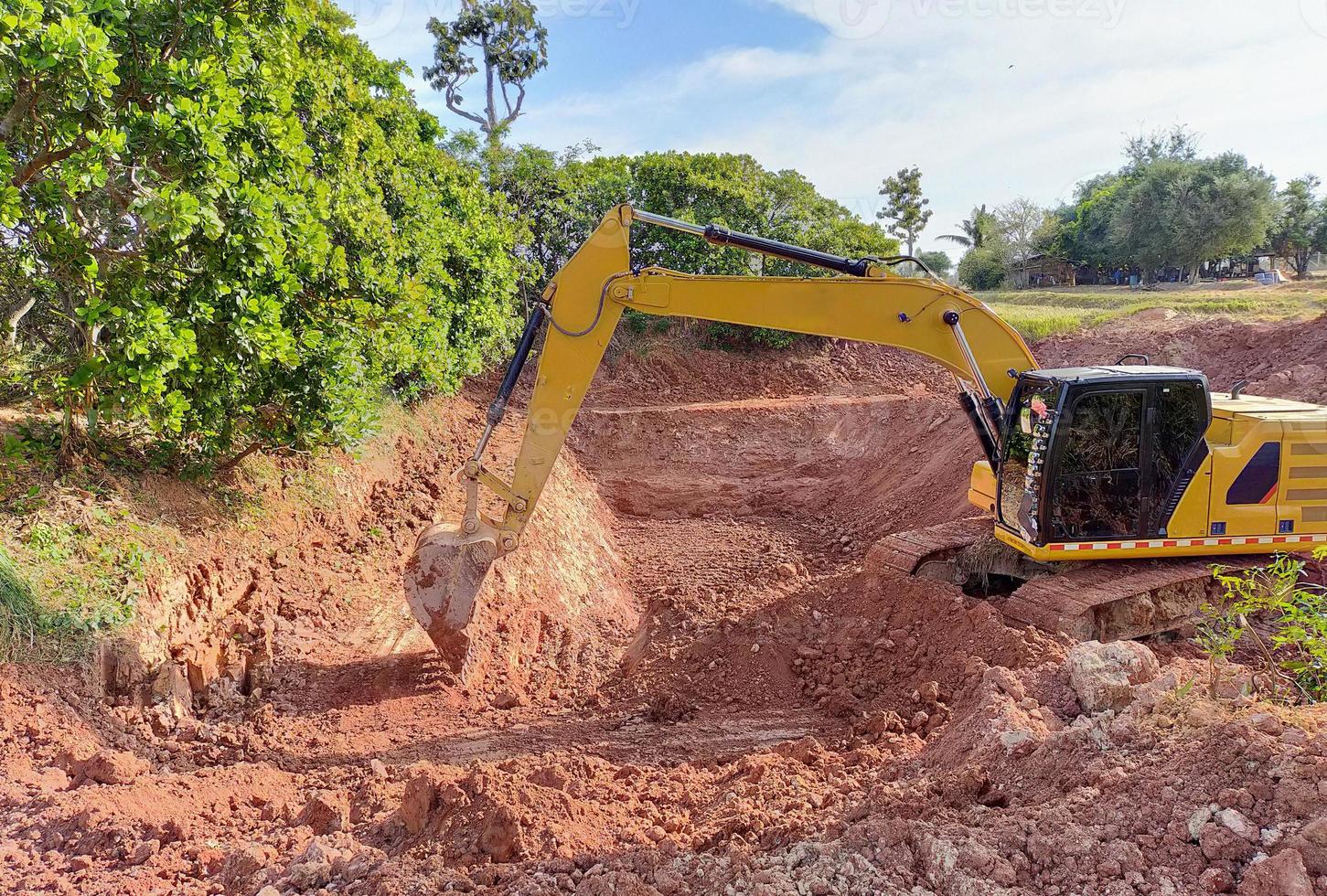 Backhoe bucket digging the soil at agriculture farm to make pond. Crawler excavator digging at shale layer. Excavating machine. Earth moving equipment. Excavation vehicle. Construction business. photo