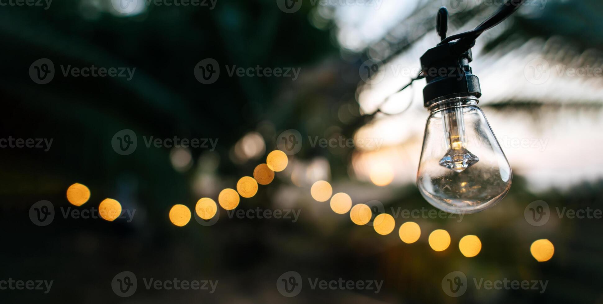 Luminous incandescent lamps hang in the form of a garland. Christmas warm gold garland lights. Festival Event Party. Garlands, light Christmas decorations background. Party and celebration concept. photo