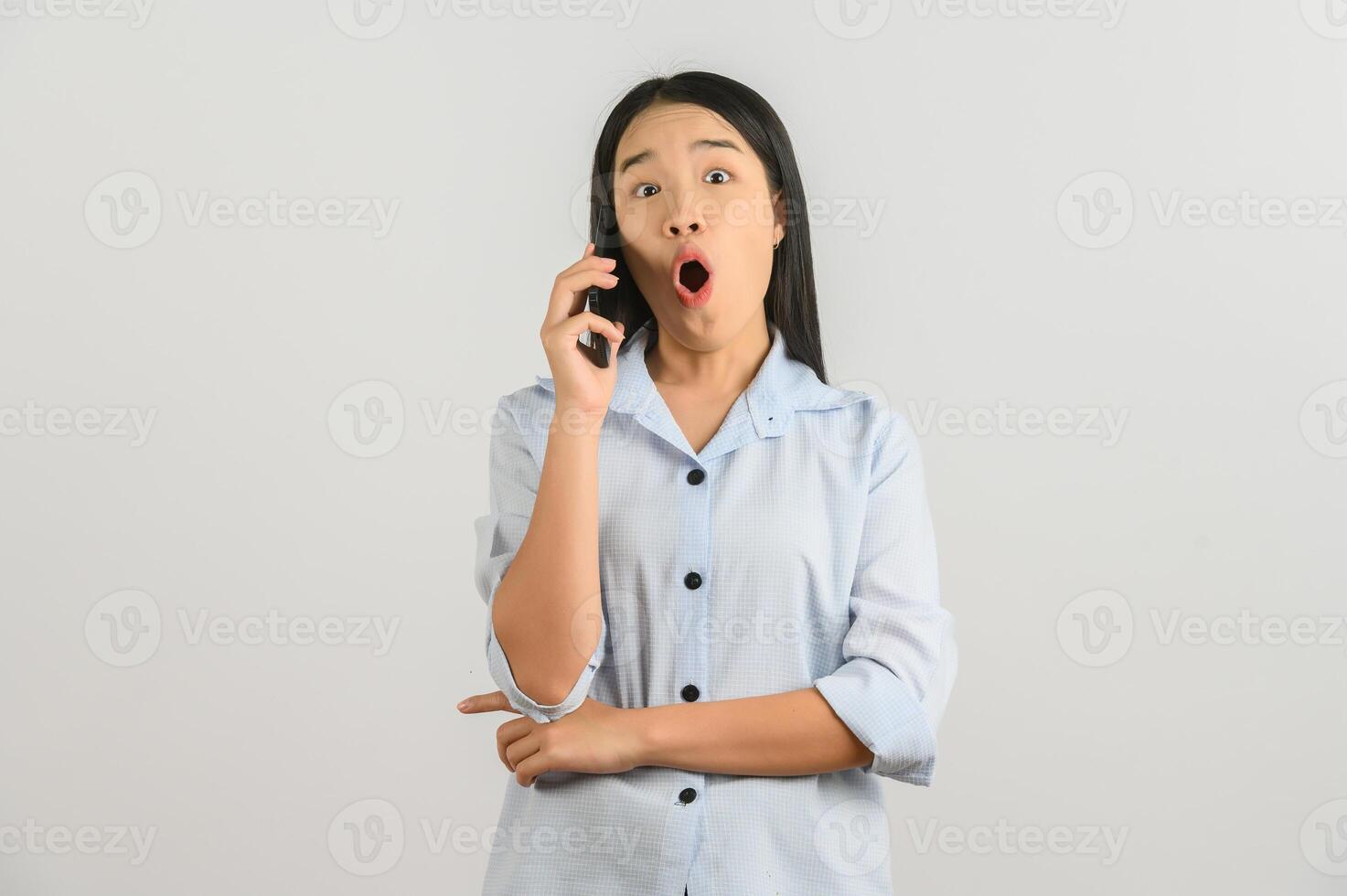 Portrait of Young asian woman talking on mobile phone while standing isolated over white background photo