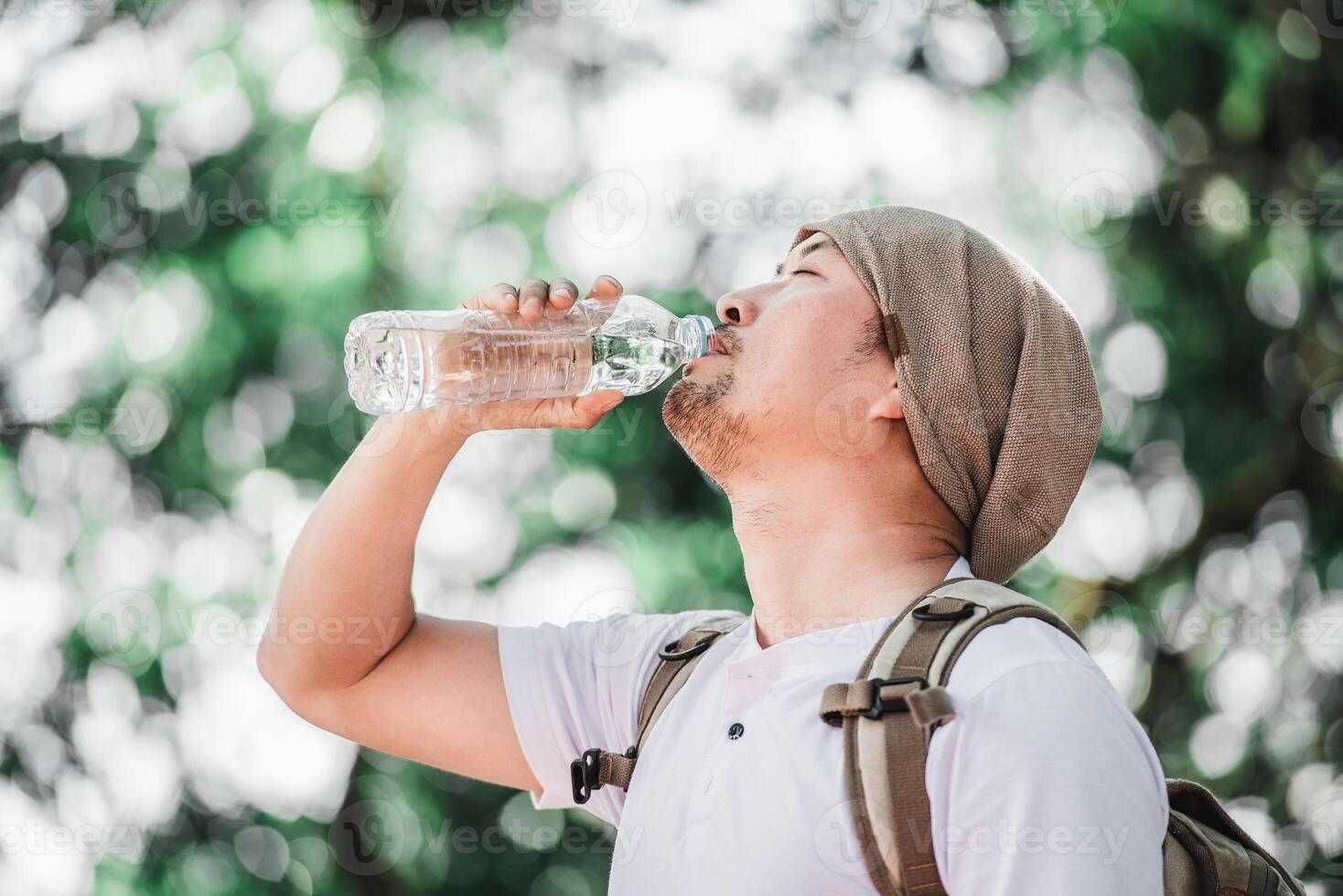 Portrait Asian traveler man with backpack drinking water photo