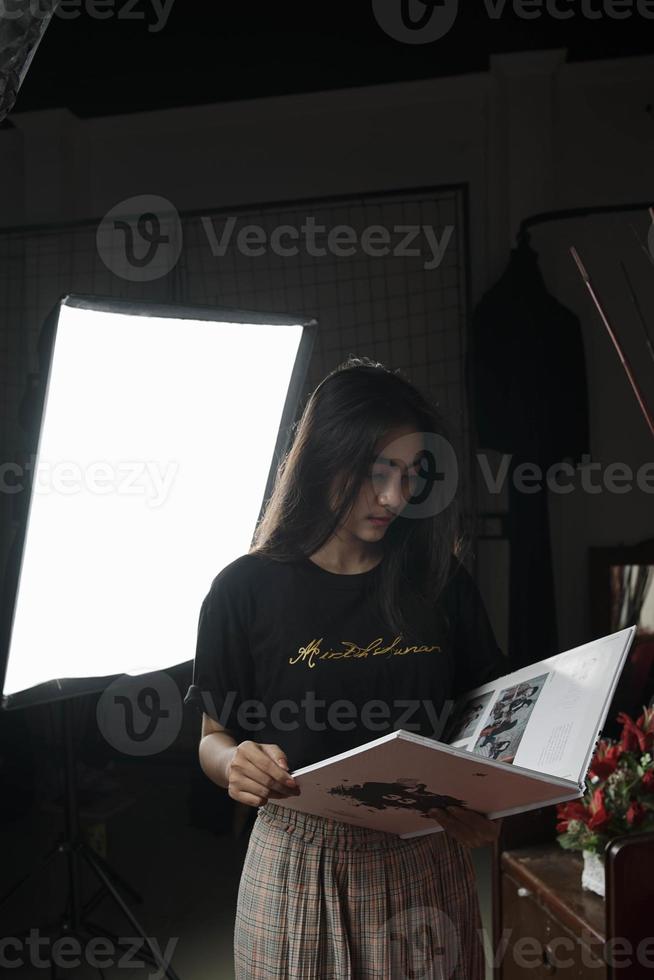 mujer asiática de indonesia leyendo un libro sobre un fondo claro. foto