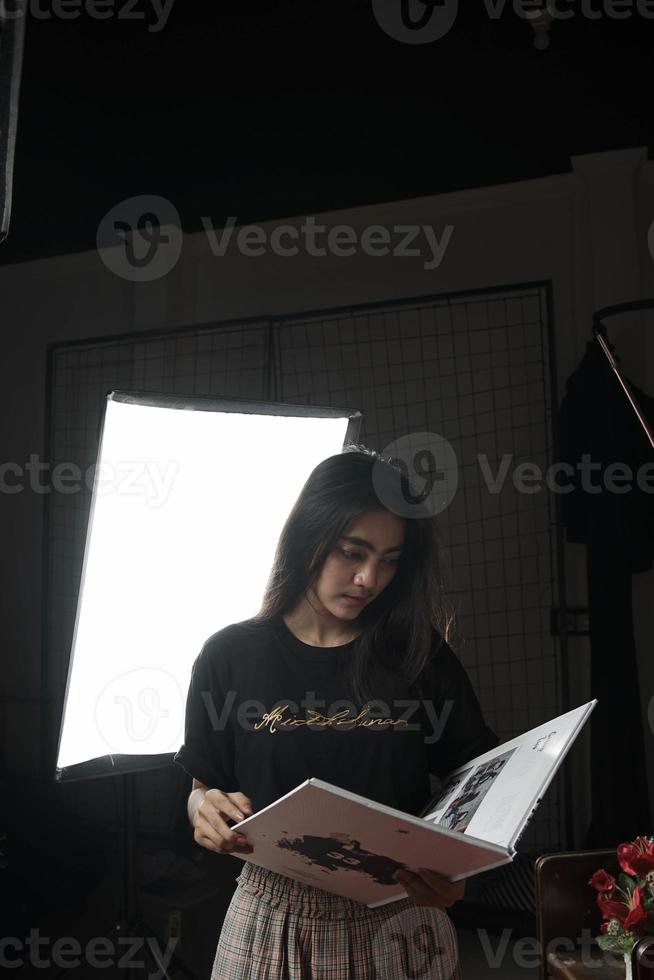 mujer asiática de indonesia leyendo un libro sobre un fondo claro foto