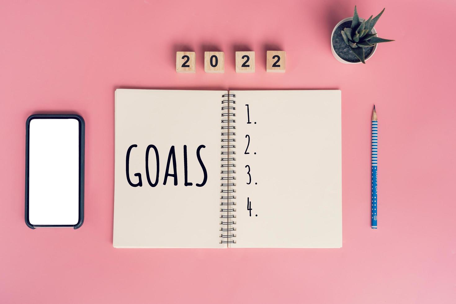 Notebooks with empty goals for 2022 year and phone on color background photo