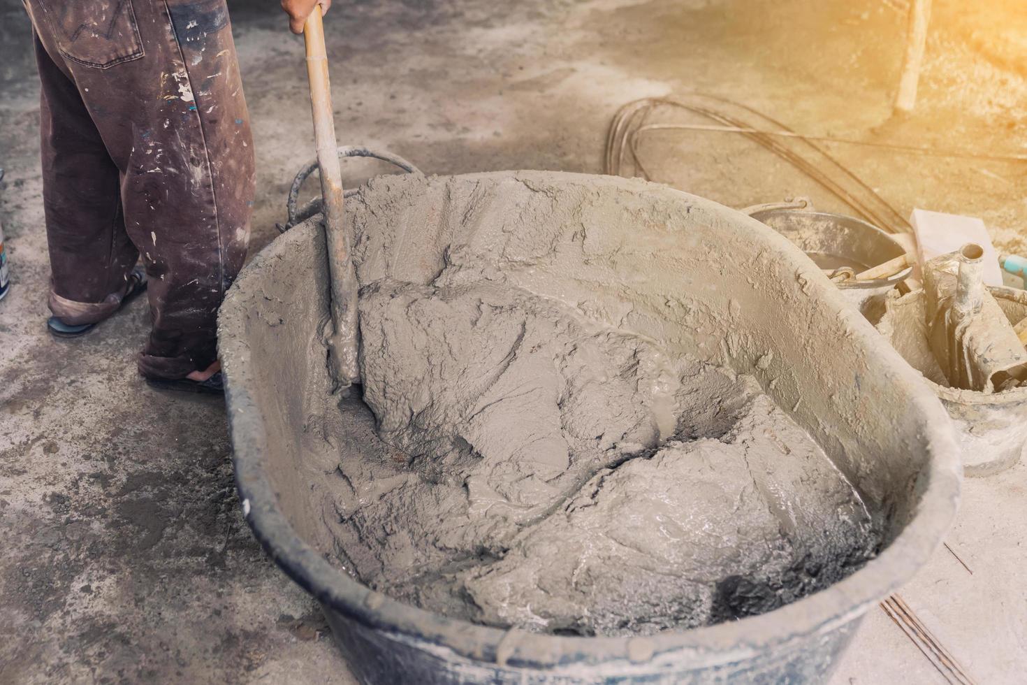 Worker man house builder mix mortar from a trough in bucket photo