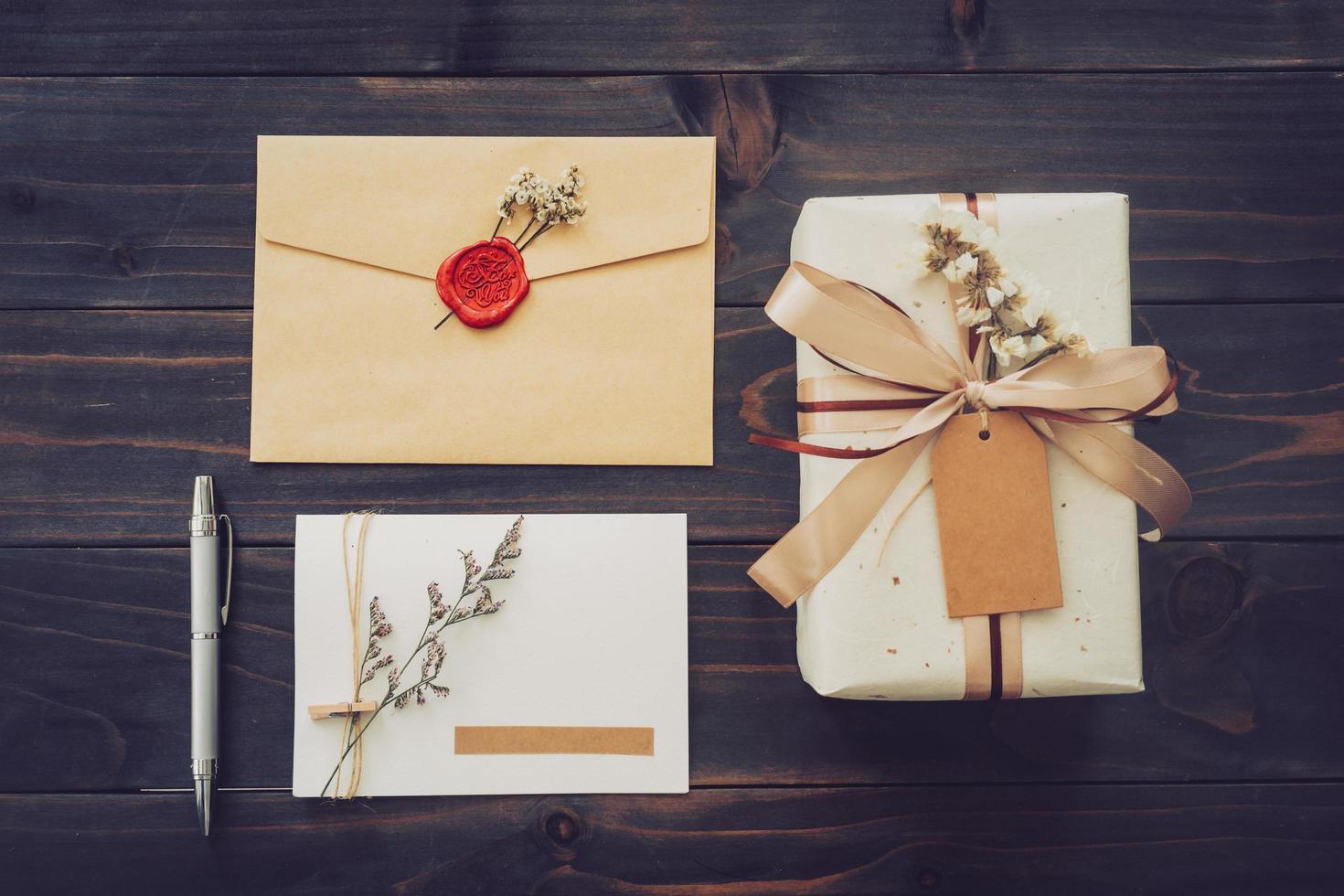 arriba de la caja de regalo artesanal y tarjeta de felicitación con bolígrafo sobre fondo de mesa de madera foto