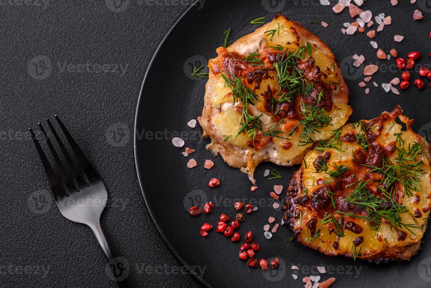 Meat baked in the oven with pineapple, tomatoes, cheese, spices and herbs photo