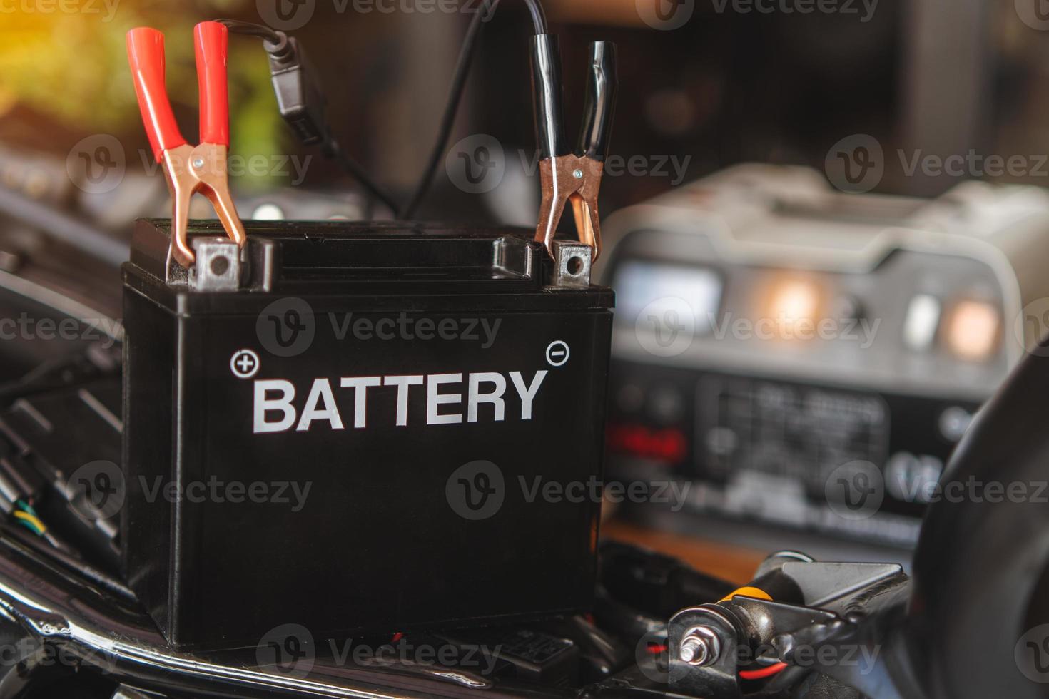 Charging motorcycle battery at garage, selective focus on Alligator clip ,concept of motorcycle maintenance and repair. photo