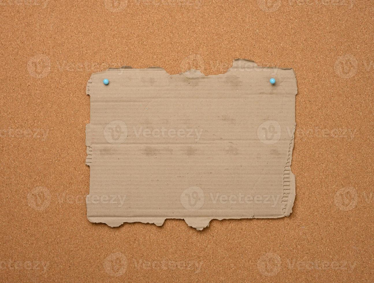 empty torn piece of brown cardboard paper pinned to a corkboard. Place for inscription photo