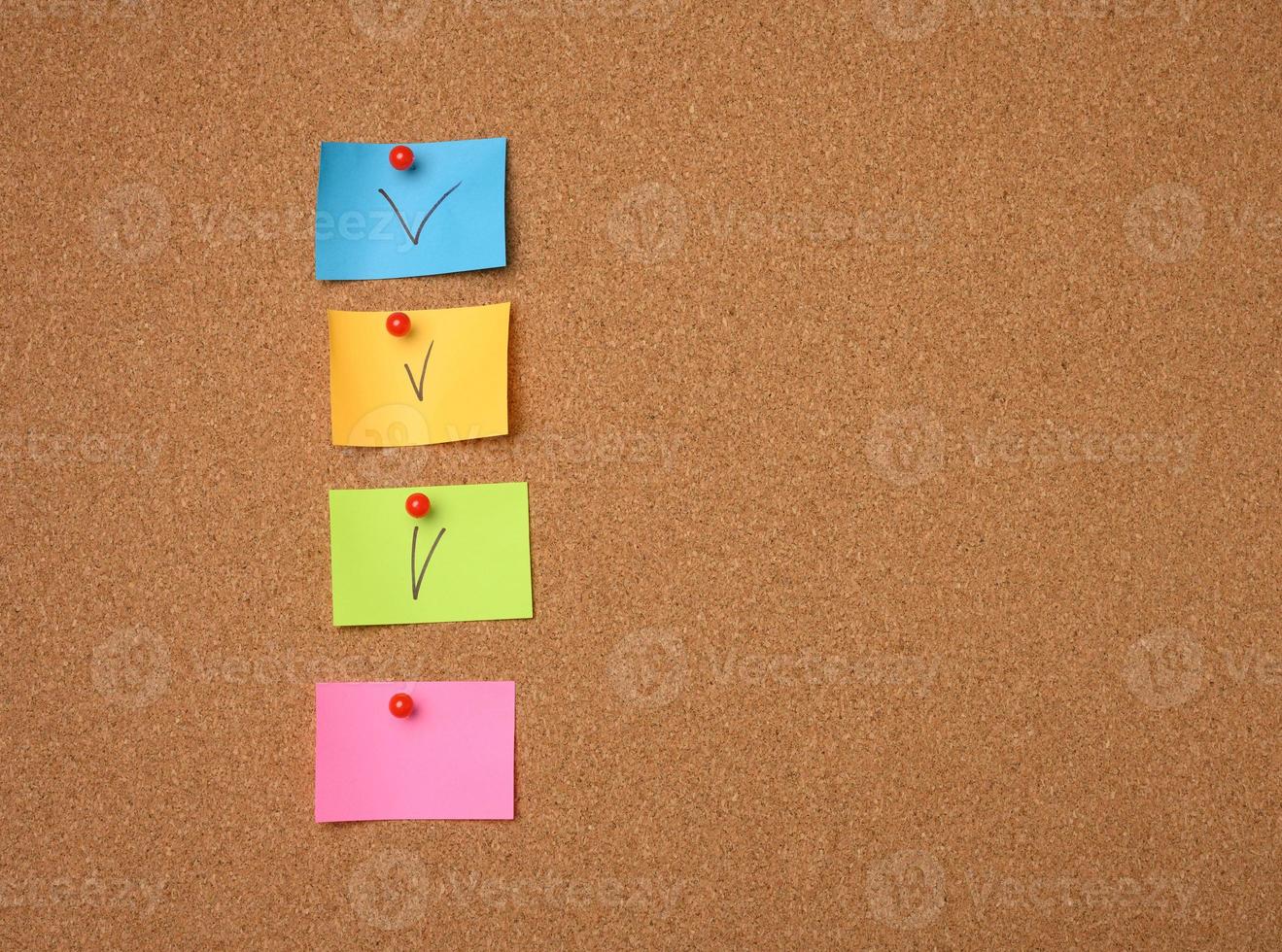 colorful paper stickers glued to brown cork board photo