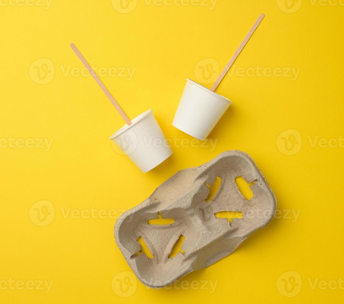disposable white paper cups, wood sticks and paper tray on yellow background photo