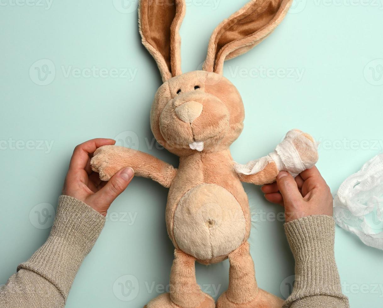 soft plush rabbit with a bandaged paw with a white medical bandage photo